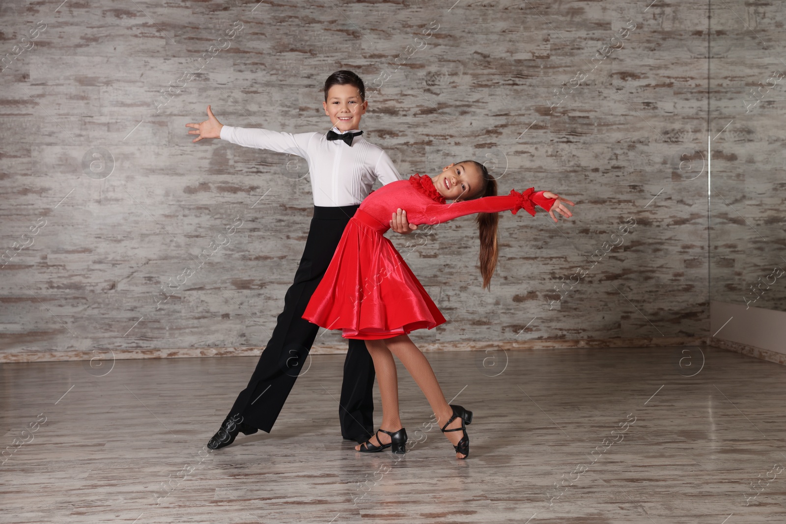 Photo of Beautifully dressed couple of kids dancing together in studio