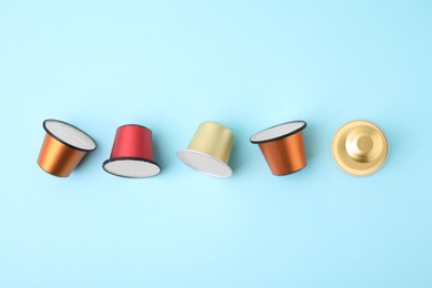 Many coffee capsules on light blue background, flat lay