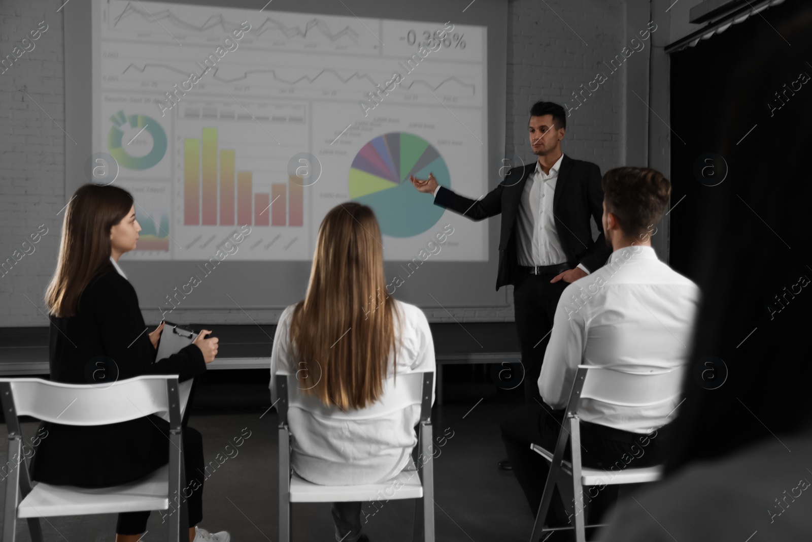 Photo of Male business trainer giving lecture in conference room with projection screen