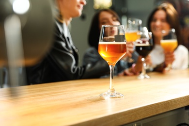 Women at bar, focus on glass of fresh beer