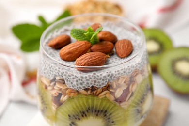 Photo of Delicious dessert with kiwi, chia seeds and almonds in glass, closeup
