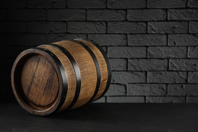 Photo of One wooden barrel on table near brick wall. Space for text