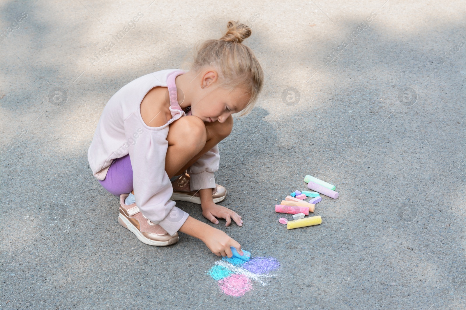 Photo of Little child drawing butterfly with chalk on asphalt