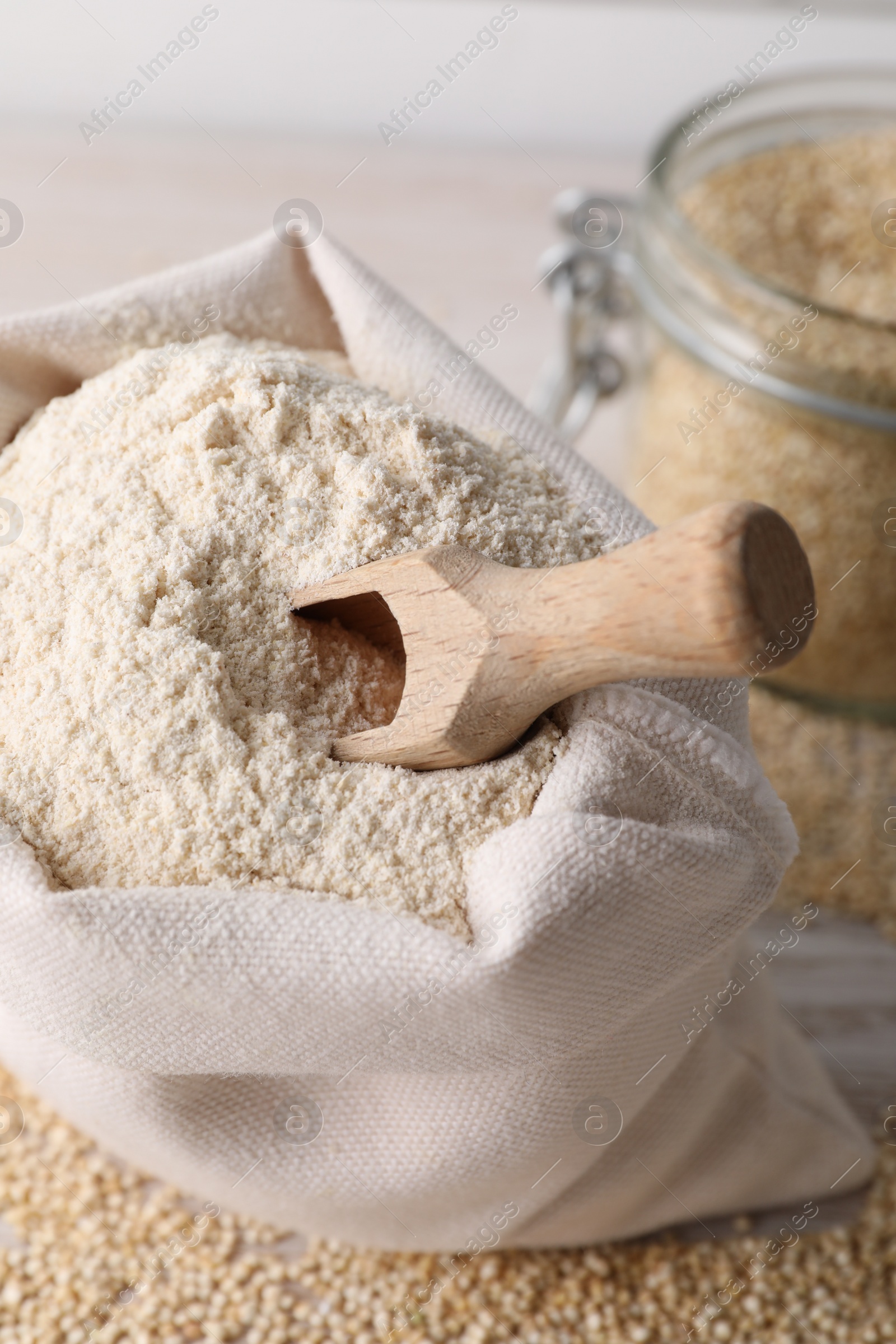 Photo of Sack with quinoa flour, scoop and seeds on white wooden table