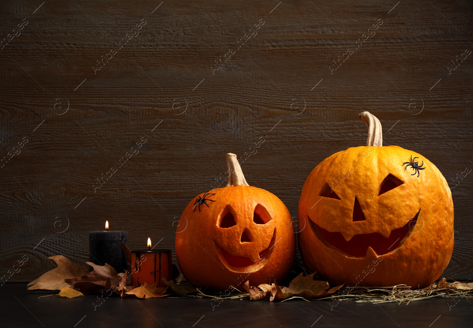 Photo of Spooky Jack pumpkin head lanterns on grey table against wooden background, space for text. Halloween decoration