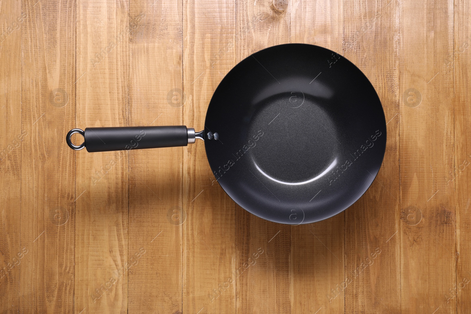 Photo of Empty iron wok on wooden table top view. Chinese cookware