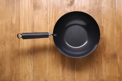 Empty iron wok on wooden table top view. Chinese cookware