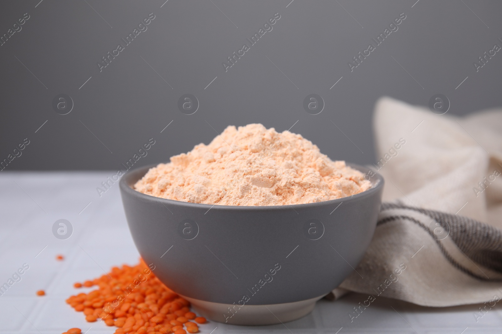 Photo of Bowl of lentil flour and seeds on white table