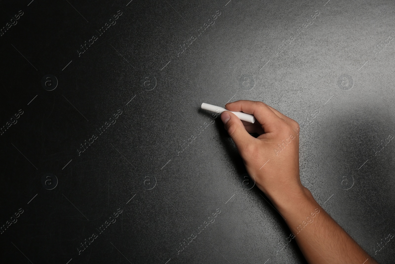 Photo of Man writing with piece of chalk on blackboard