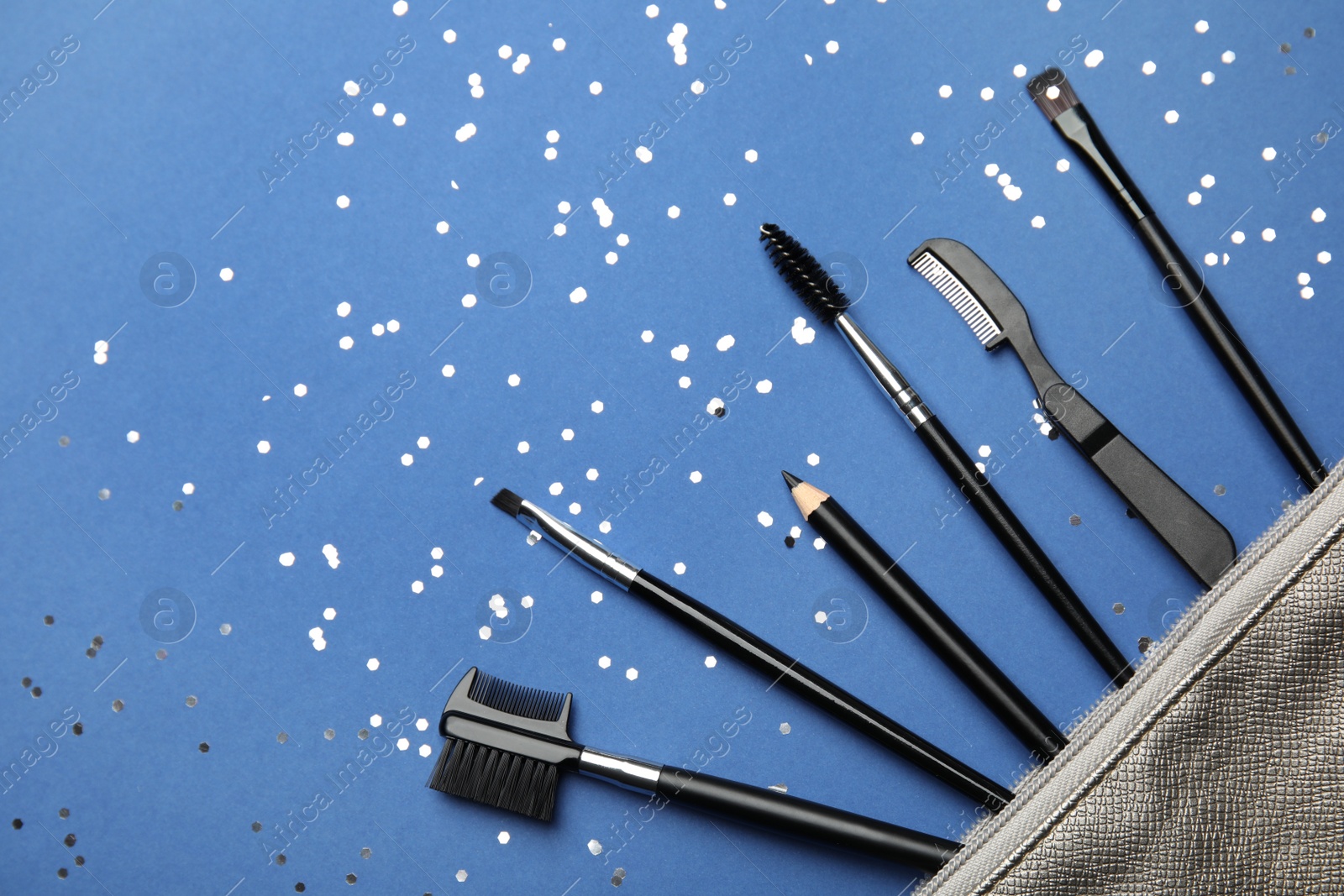 Photo of Flat lay composition with professional eyebrow tools on blue background, space for text