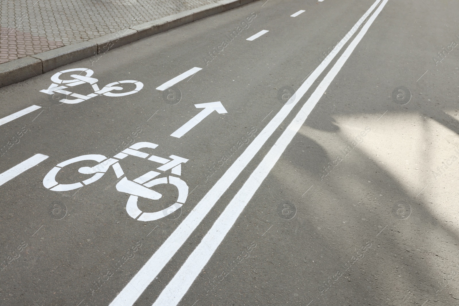 Photo of Two way bicycle lane with white signs on asphalt