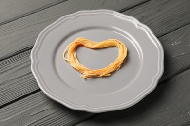 Heart made with spaghetti on grey wooden table