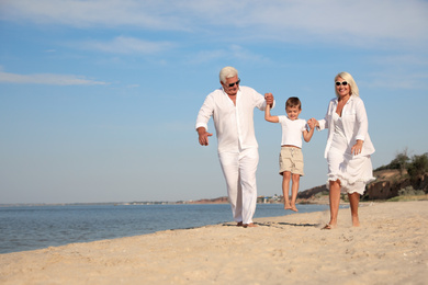 Cute little boy with grandparents spending time together on sea beach