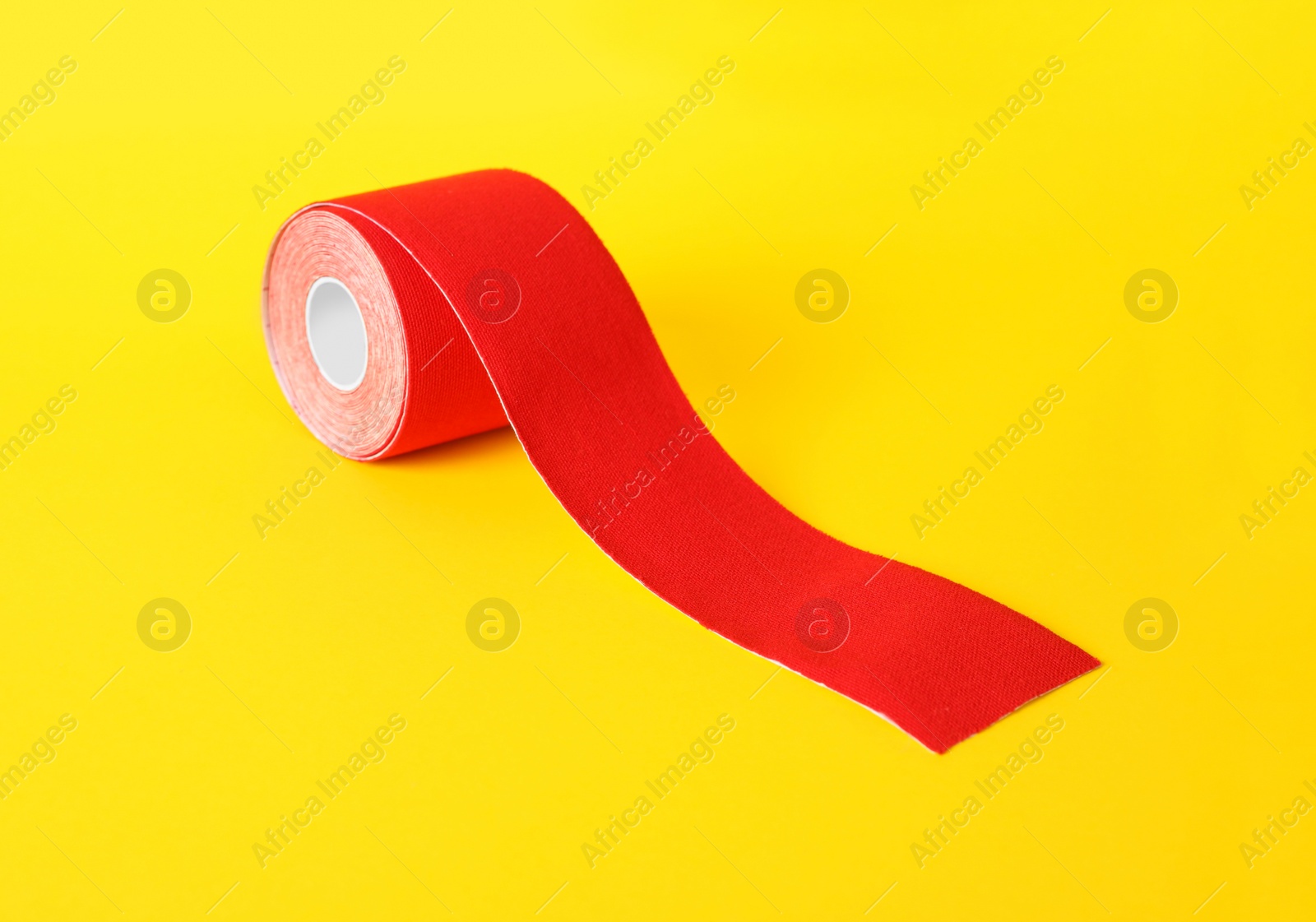 Photo of Red kinesio tape in roll on yellow background