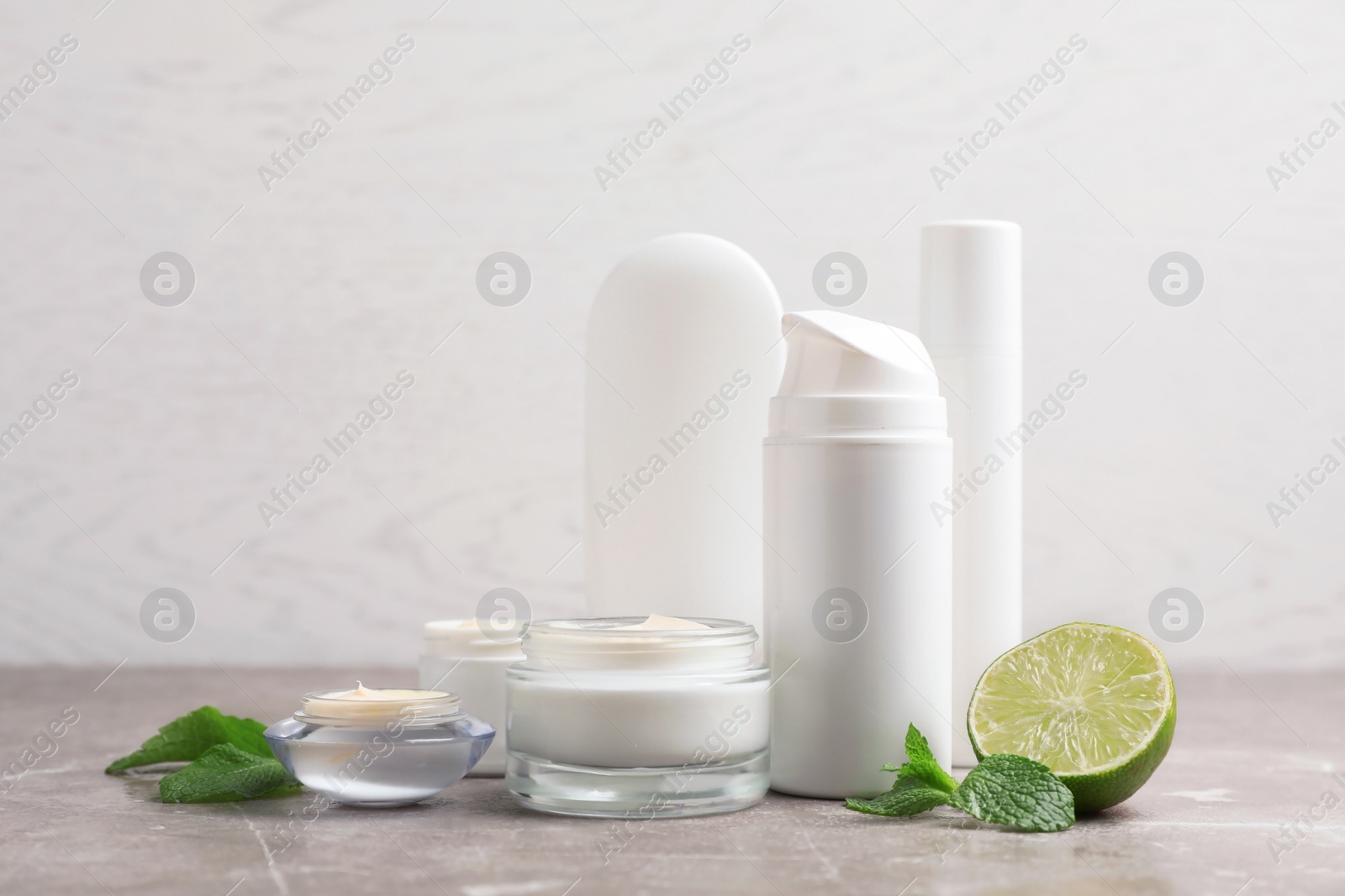 Photo of Jars with cream and bottles on gray table. Hand care cosmetics