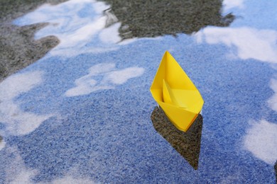 Photo of Beautiful yellow paper boat on water outdoors, space for text