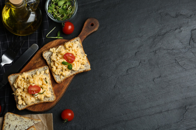 Tasty scrambled egg sandwiches served on black table, flat lay. Space for text