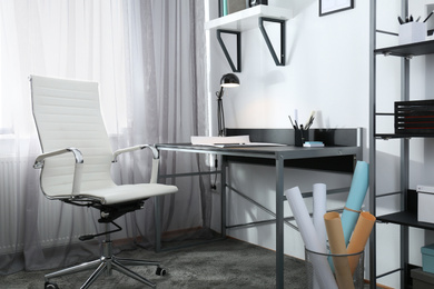 Photo of Stylish room interior with comfortable workplace near window. Design idea