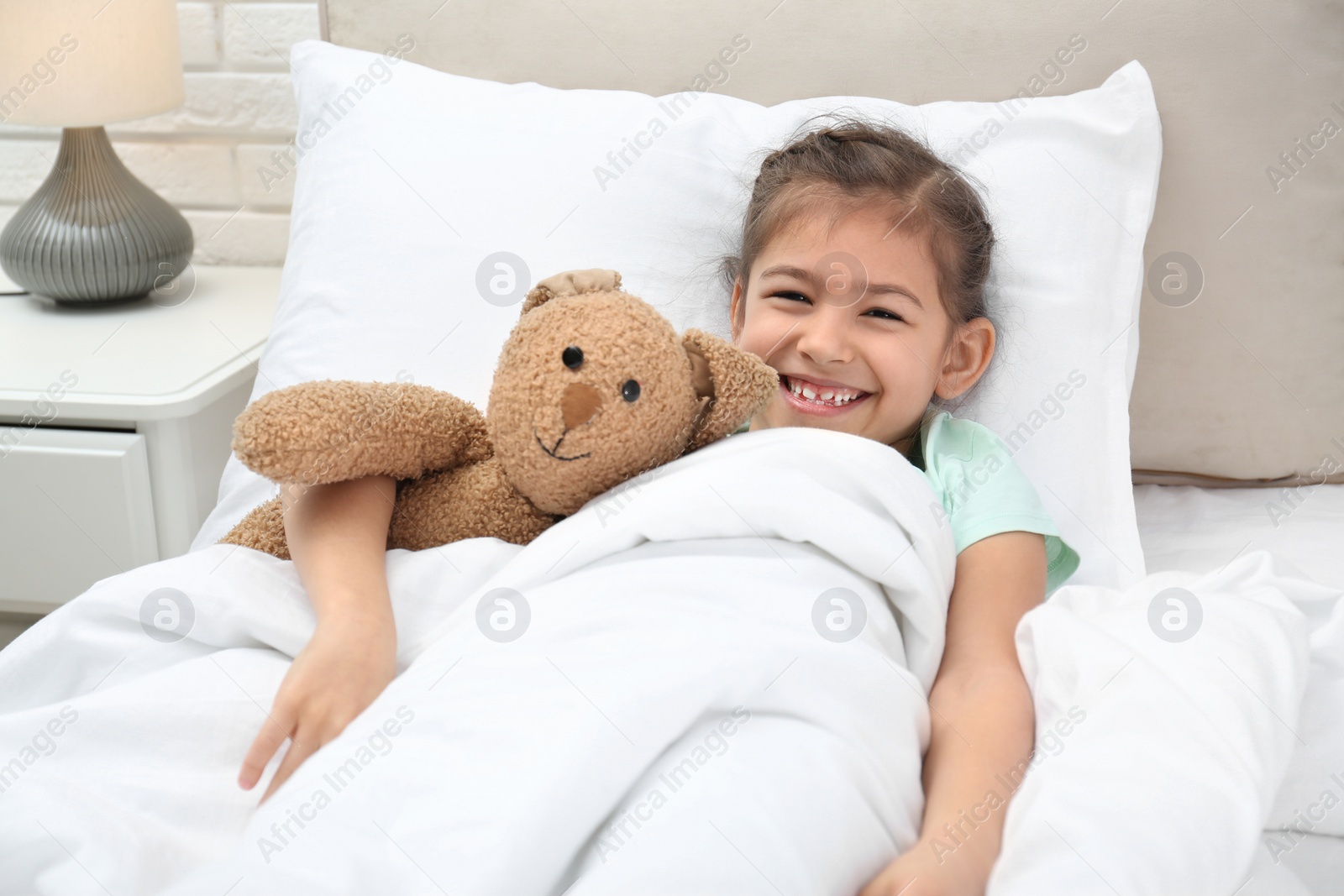 Photo of Cute child with stuffed bunny resting in bed at hospital