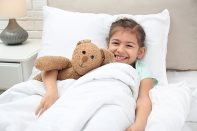 Cute child with stuffed bunny resting in bed at hospital