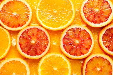 Photo of Slices of fresh citrus fruits as background, top view