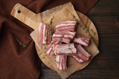 Photo of Cut raw pork ribs with thyme on wooden table, top view