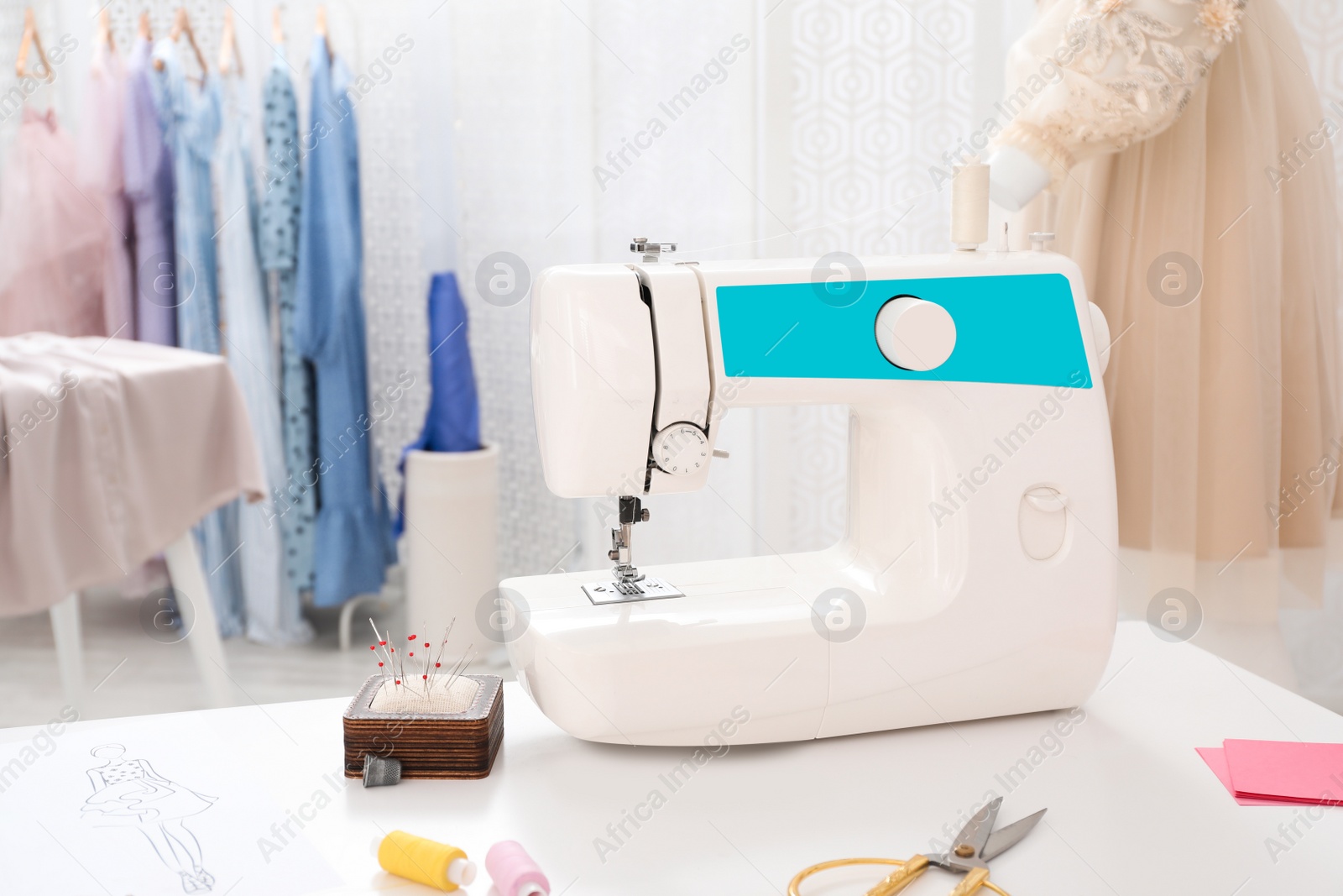 Photo of Modern sewing machine and accessories on table in dressmaking workshop
