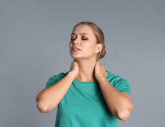 Photo of Woman suffering from neck pain on grey background