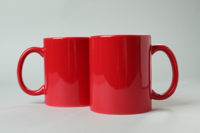 Two red ceramic mugs on light grey background