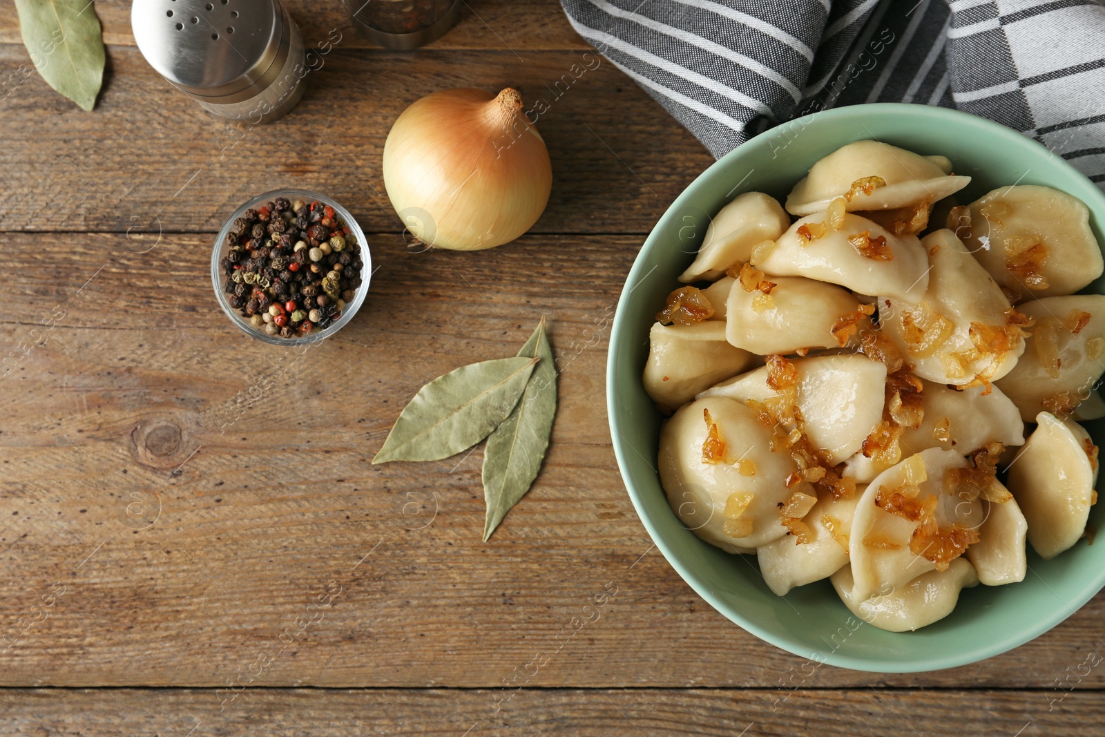 Photo of Delicious cooked dumplings with fried onion on wooden table, flat lay