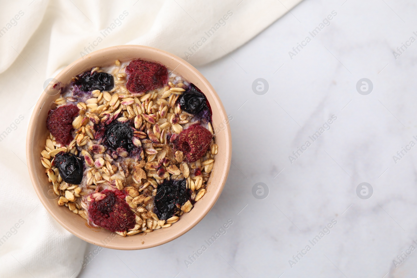 Photo of Tasty baked oatmeal with berries on white marble table, top view. Space for text