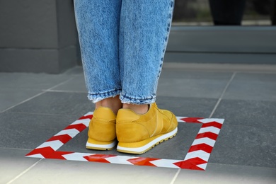 Woman standing on taped floor marking for social distance, closeup. Coronavirus pandemic