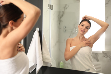 Photo of Young woman touching soft underarm skin after shaving in bathroom