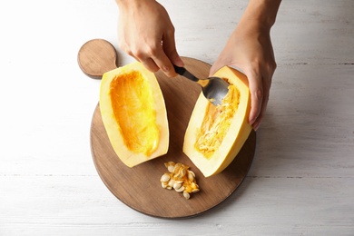 Photo of Woman removing seeds from spaghetti squash on table, top view