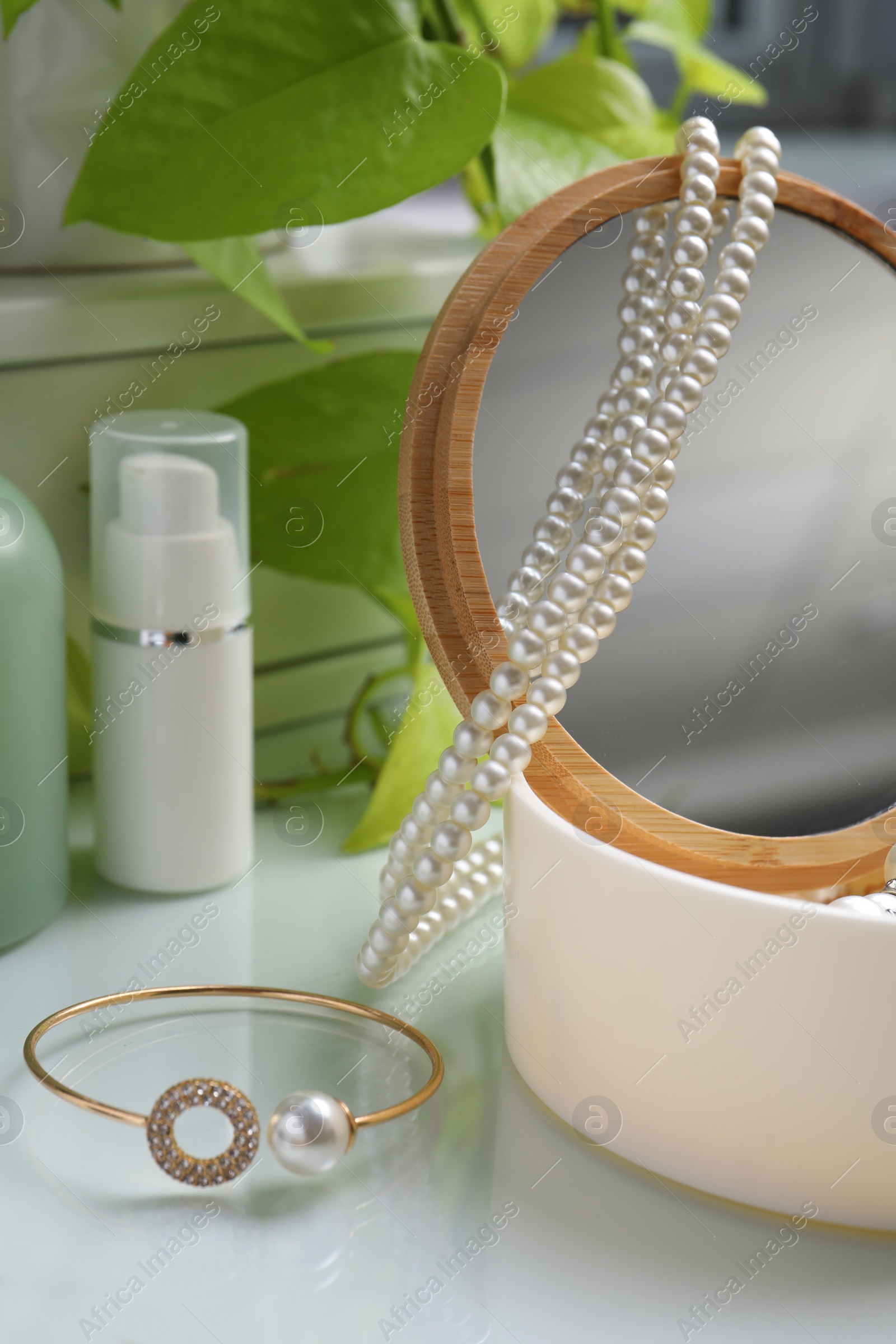 Photo of Stylish jewelry with pearls in box and cosmetic products on white table