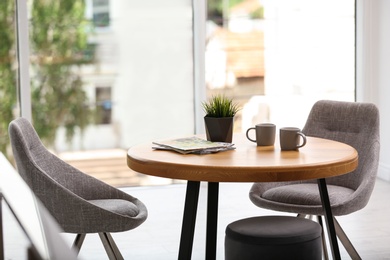 Stylish room interior with round table and comfortable chairs