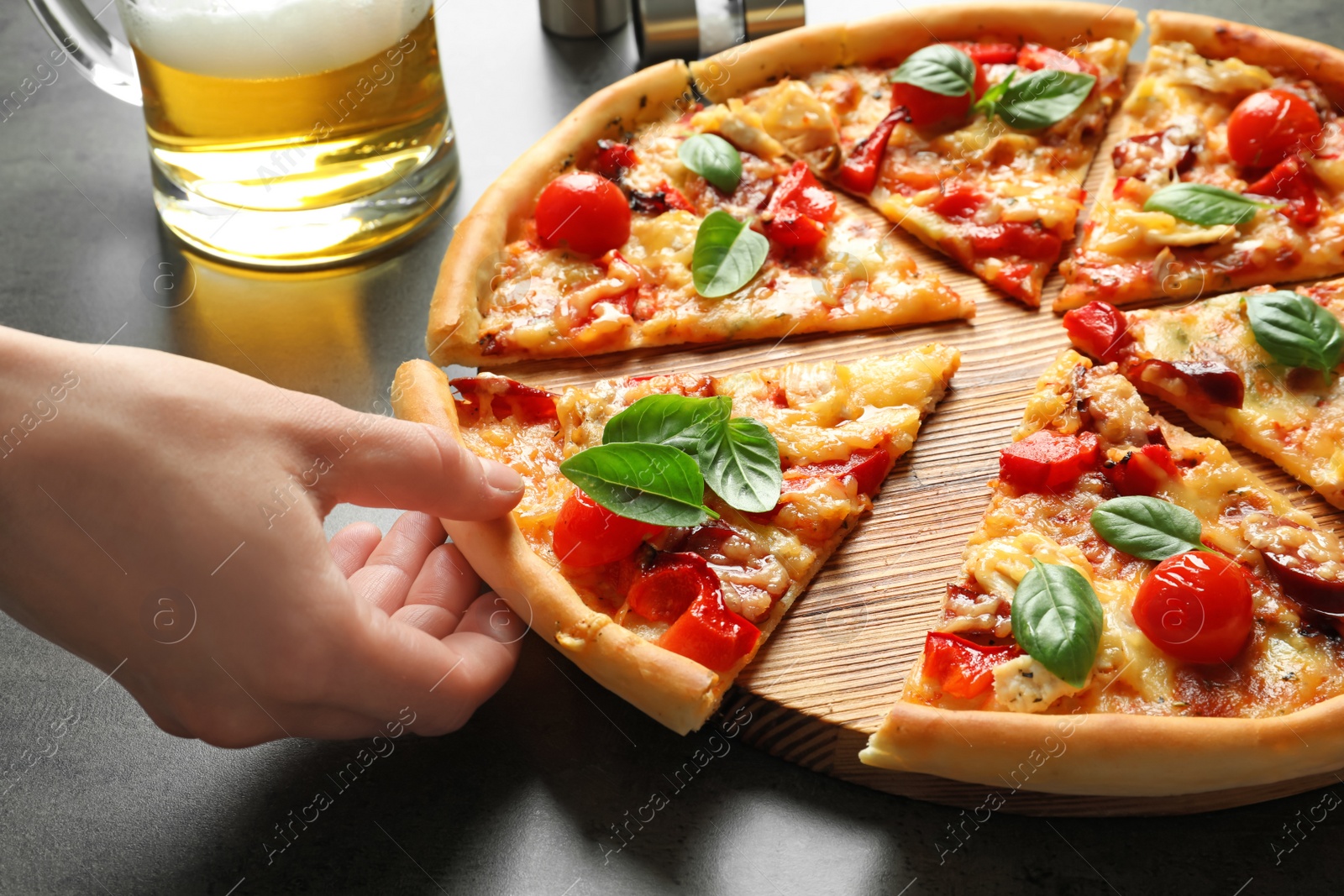 Photo of Man taking slice of delicious pizza with tomatoes and sausages at table