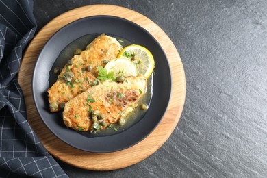 Delicious chicken piccata on black table, top view