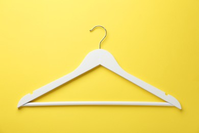 Photo of White hanger on yellow background, top view
