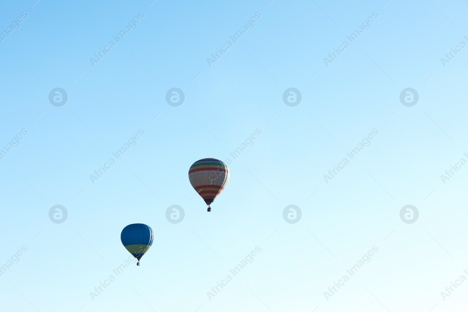 Photo of Colorful hot air balloons flying in blue sky. Space for text