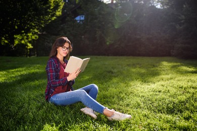 Photo of Young woman reading book in park on sunny day