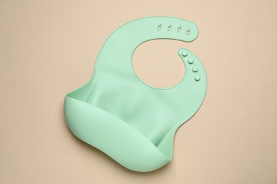 Photo of Green silicone baby bib on beige background, top view. First food
