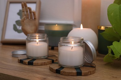 Photo of Burning candles, houseplant and decor elements on wooden table indoors