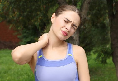 Young woman suffering from neck pain outdoors