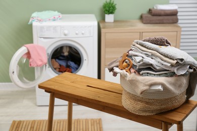 Photo of Laundry basket with baby clothes and toy on table in bathroom. Space for text