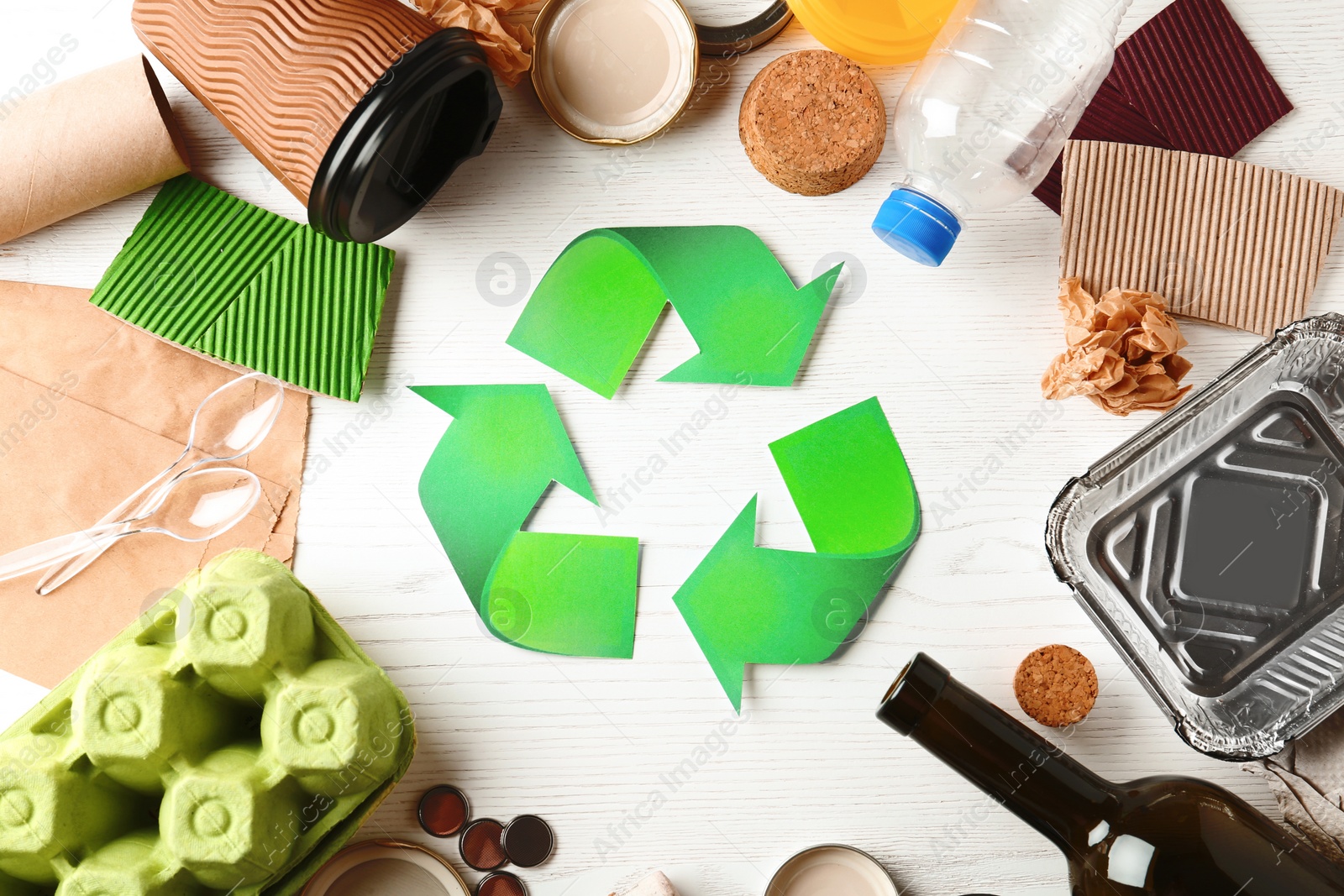 Photo of Recycling symbol and different garbage on wooden background, top view