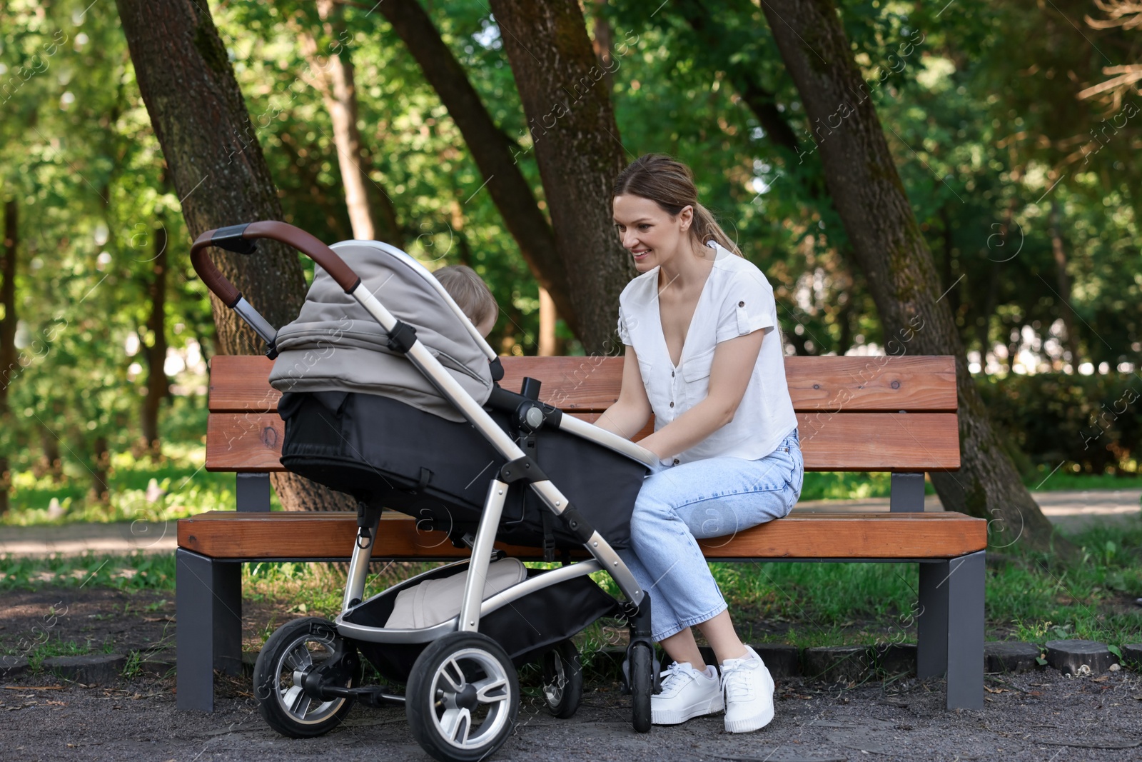 Photo of Happy nanny with baby in stroller in park