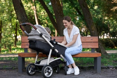 Photo of Happy nanny with baby in stroller in park