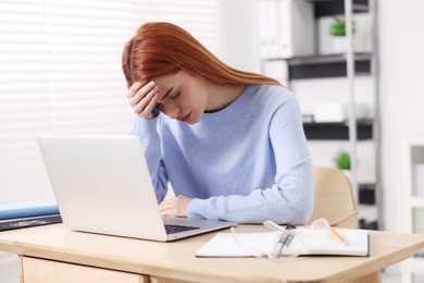 Photo of Woman suffering from headache at workplace in office