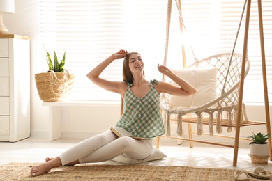 Photo of Woman sitting near comfortable hammock chair at home